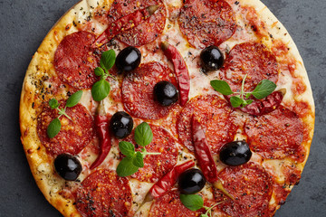 Pizza with salami, black olives, pepper and fresh herbs. Top view.