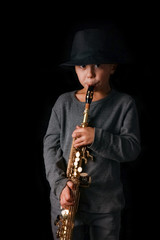 Fototapeta premium happy child plays saxophone in studio