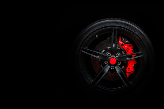 Isolated generic sport car wheel with red breaks drifting and smoking on a black background