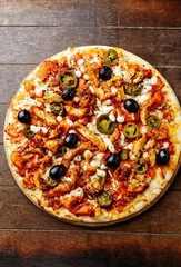 Chicken Gyro Pizza jalapeno pepper, black olives and fresh gerbs. Brown wooden background. Top view. 
