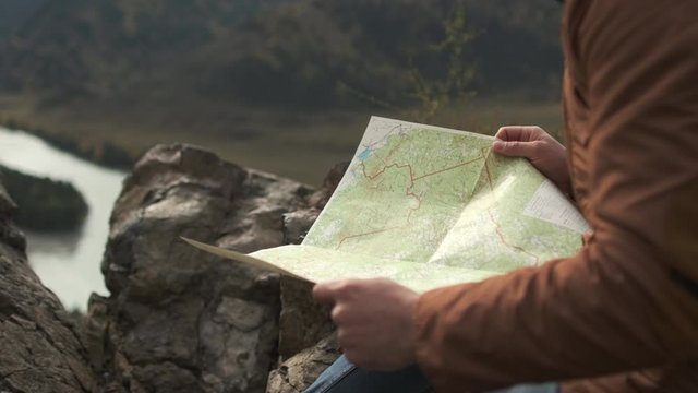 Close up of hands of hiker tourist traveler man looking for map route, traveling on mountain. Active lifestyle hiking enjoying vacation travel tourism backpacking adventure landscape nature 4 K slowmo