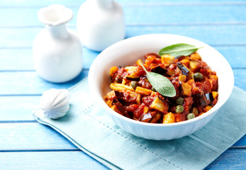 Penne pasta with vegetable sauce and fresh herbst. Bright background.
