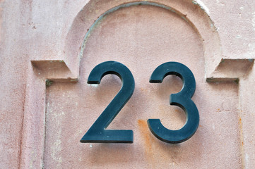 A house number plaque, showing the number twenty three (23)