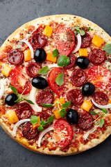 Pizza with sausage, black olives, tomatoes, orange peper and fresh herbs. Home made food. Concept...