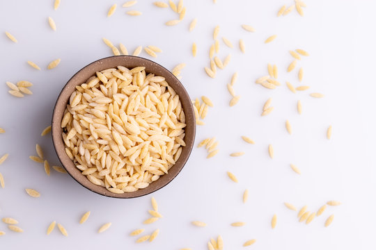 Orzo pasta, isolated on white background. Italian orzo pasta shaped like grains of rice, copy space, soft light