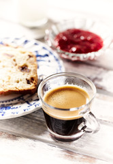 Coffee in glass cup, sliced yeast cakeand jam on bright background. 