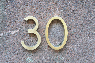 A house number plaque, showing the number thirty (30)