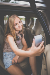 Obraz na płótnie Canvas Cute teenage girl listening to her favorite music/audiobook on hig-end headphones during a roadtrip