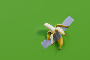 Yellow bitten banana is taped to the green  wall