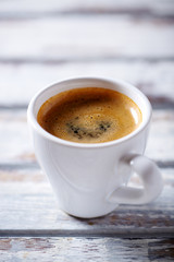 Cup of coffee on bright wooden background. 