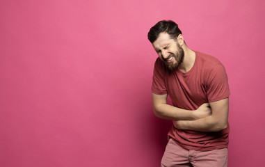 A bearded man has a stomach ache.