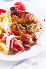 Spicy Chicken Wings with french fries, tomatoes and kalamata olives. Bright background.