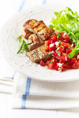 Fried pork tenderloin with tomato salsa. Bright background. 