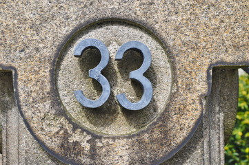 A house number plaque, showing the number thirty three (33)