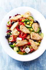 Healthy Salad with Chicken Briest, Feta Cheese, Blcak Olives, Cucumber, Red Pepper and Sweet Corn. Bright wooden background. 