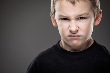 Fototapeta premium Loads of aggression in a little boy - education concept hinting behavioral problems in young children (shallow DOF)