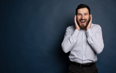 Happy bearded businessman looking at camera on blue background with copy space.