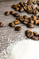 Coffee beans and sugar on the wooden table.