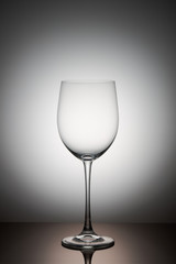 One empty transparent wine glass stands on a dark glass