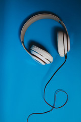 White audio headphones, isolated on blue background.
