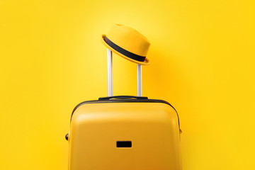 Suitcase with hat over  yellow background minimal creative travel concept