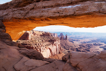 View through the glowing Mesa Arch towards the Washerwoman Arch in the center and the La Sal mountains in the distance
