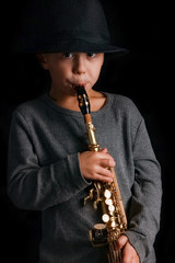 happy child plays saxophone in studio