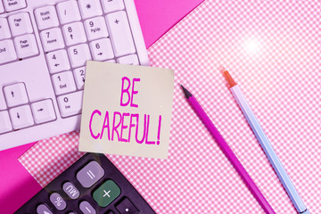 Writing note showing Be Careful. Business concept for making sure of avoiding potential danger mishap or harm Note paper stick to keyboard near colored gift wrap on table