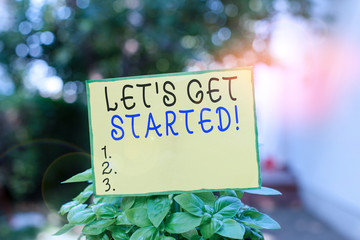 Writing note showing Let S Get Started. Business concept for encouraging someone to begin doing something Plain paper attached to stick and placed in the grassy land