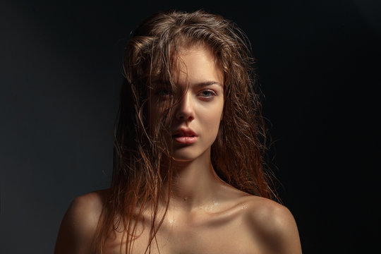 Beauty portrait of a young attractive girl with wet hair on a dark background.