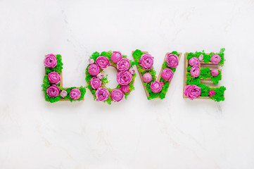 Flower composition with volume letters LOVE with stabilized moss and roses on marble background