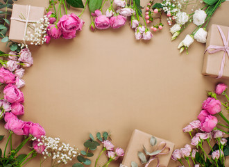 Frame of flowers and gift boxes on craft paper background