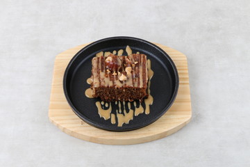 Chocolate and Date cake with nuts on black and wood plate on a white texture background 