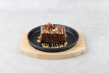 Chocolate and Date cake with nuts on black and wood plate on a white texture background 
