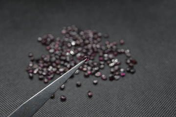 Red Rhodolite garnet in a fancy form on a vise and a black fabric background.
