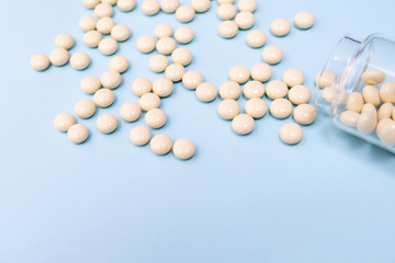 Fighting against cancer, tablets for chemotherapy in glass transparent bottle on blue background, copy space