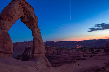 Delicate Arch with cars exiting the park in the background
