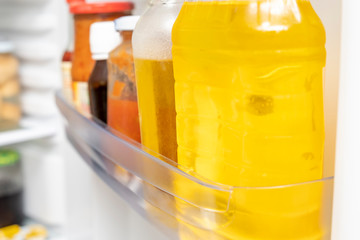 Different bottles with sauces and oils on a freezer, frige refrigerator door close up