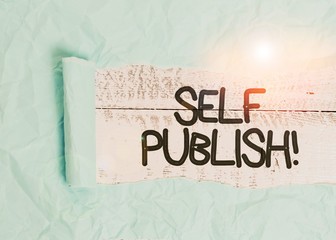 Text sign showing Self Publish. Business photo text writer publish piece of ones work independently at own expense Cardboard which is torn in the middle placed above a wooden classic table