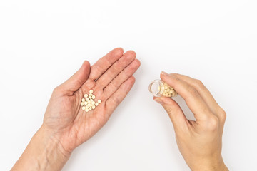 Hands holding a glass bottle and pills on a palm, patient taking pills and following doctor prescription
