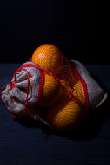 oranges in a linen bag on a dark background
