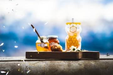 sweet honey in glass jars with spoon and flowers