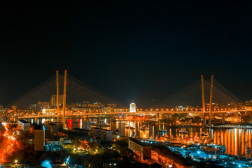 Fototapeta premium Panorama of the city of Vladivostok. Panoramic view of the Golden Horn and the central part of Vladivostok from one of the hills of the city at sunset time.