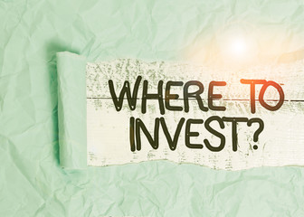 Text sign showing Where To Invest Question. Business photo text asking about where put money into financial schemes or shares Cardboard which is torn in the middle placed above a wooden classic table