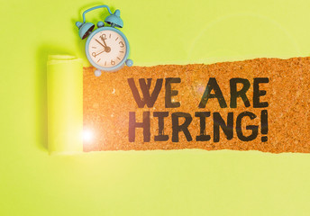 Conceptual hand writing showing We Are Hiring. Concept meaning recently you employ someone or pay someone to do particular job Alarm clock and torn cardboard on a wooden classic table backdrop