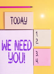 Handwriting text We Need You. Conceptual photo asking someone to work together for certain job or target Colored empty papers with copy space on the yellow background table