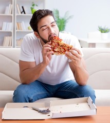 Man eating pizza having a takeaway at home relaxing resting