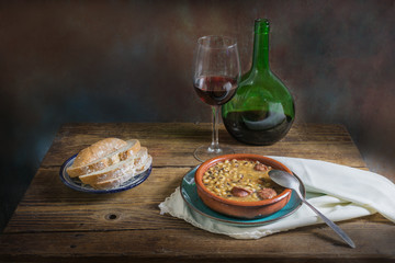 Still life of white beans with wine and bread on an old wooden background, dark food photography