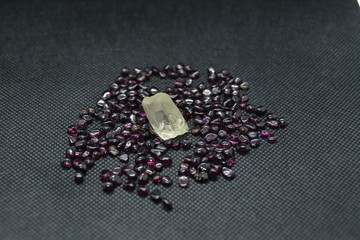 Natural quartz crystal on a natural rhodolite garnet and on a black fabric background.