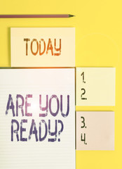 Handwriting text Are You Ready Question. Conceptual photo used telling someone start something when feel prepared Colored empty papers with copy space on the yellow background table